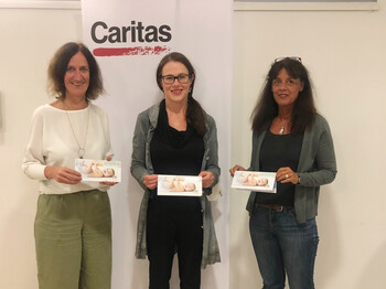 Drei Frauen vor einem Caritas Roll-Up