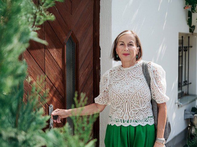 Portrait einer Haussammlerin, die an einer Eingangstüre eines traditionellen Wohnhauses in Tirol steht.