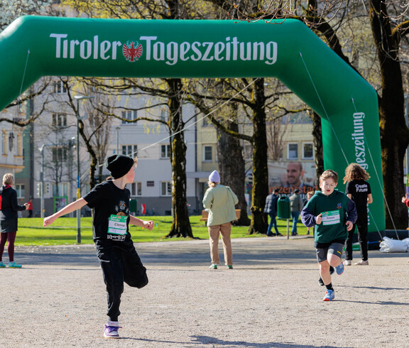 Zwei Schüler laufen vor einem Werbebogen der Tiroler Tageszeitung.