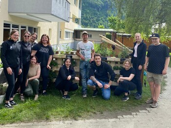 Ein Gruppenfoto von elf Personen in einem Garten.