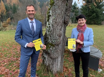 Ein Mann und eine Frau präsentieren eine Broschüre