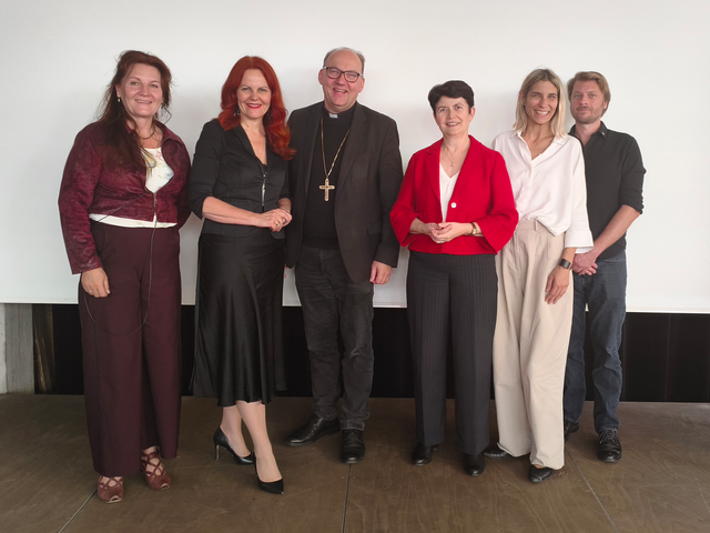Sechs Personen stehen vor einer weißen Wand zu einem Gruppenfoto zusammen.