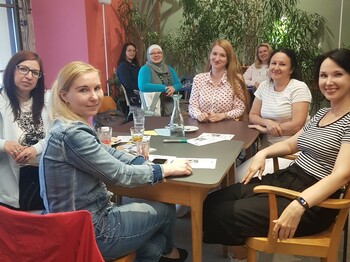 Frauen-Erzählcafé Acht Frauen sitzen um einen Tisch und schauen in die Kamera.