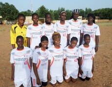 Die Sportwochen bieten Frauen die Möglichkeit, sich aus dem traditionellen Frauenbild in Mali zu befreien.  © Caritas Eine Mädchenfußballmannschaft in Mali posiert gemeinsam für ein Foto. Sie tragen weiße Trikots und stehen auf einem Sportplatz.