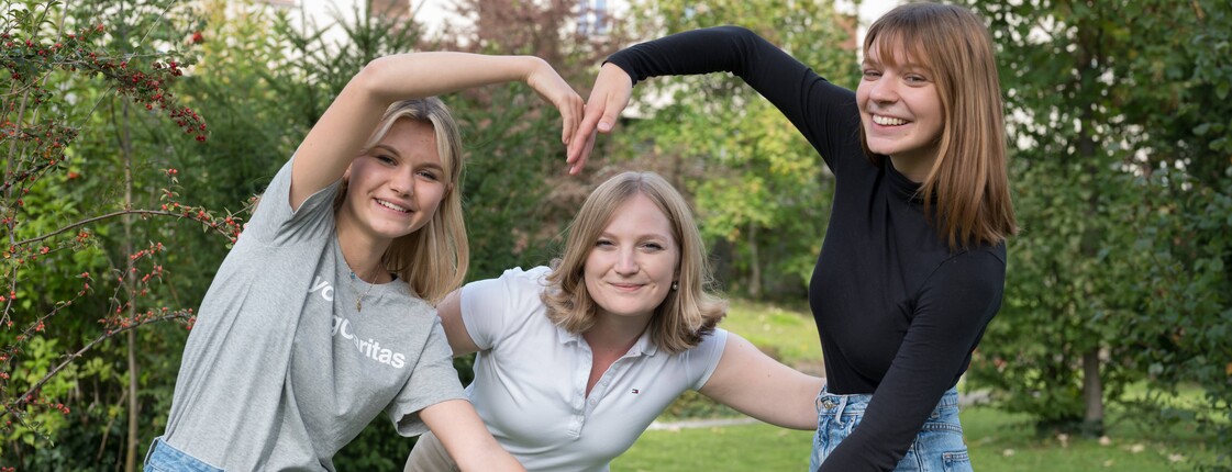 Portrait dreier Frauen, die mit ihren Händen ein Herz formen.