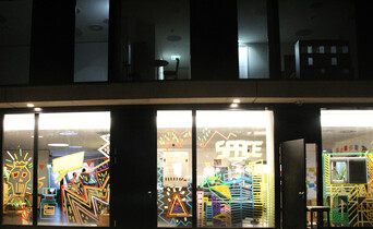 Eine beleuchtete, künstlerisch verzierte Außenfassade bei Nacht fotografiert.