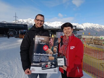 Ein Mann und eine Frau präsentieren ein Plakat mit Kampagnensujet.