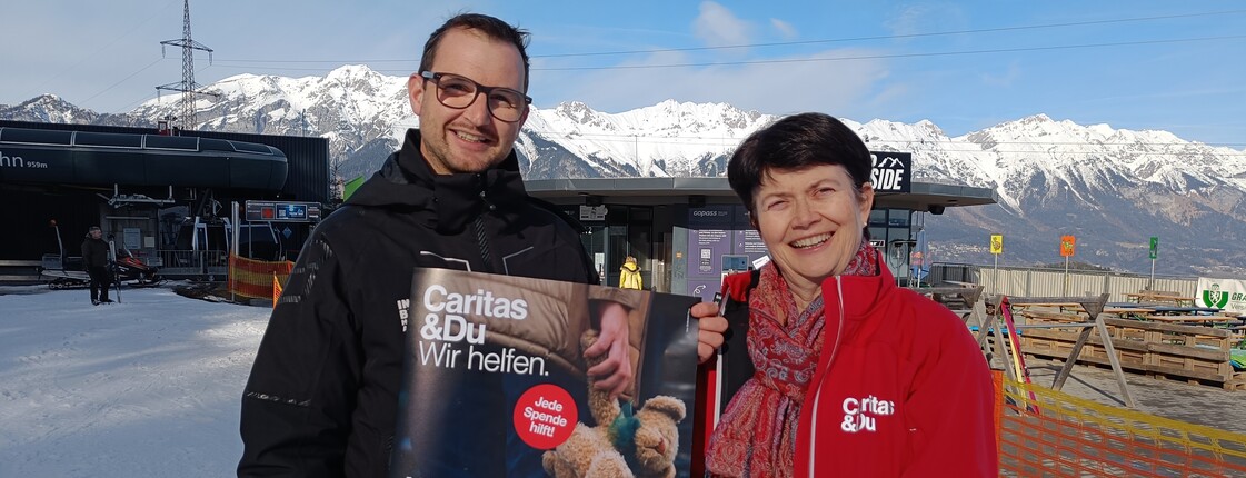 Ein Mann und eine Frau präsentieren ein Plakat mit Kampagnensujet.