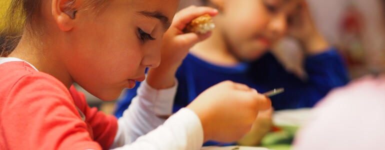 Zwei Kinder essen eine warme Gemüsesuppe.