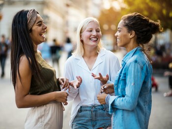 Vortrag: Interkulturelle Kommunikation Drei lachende Frauen unterschiedlicher Herkunft unterhalten sich.