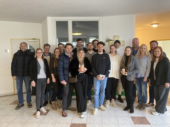 Studierende und Mitarbeiter*innen des Caritas-Zentrums stehen in einem Raum zu einem Gruppenfoto zusammen.