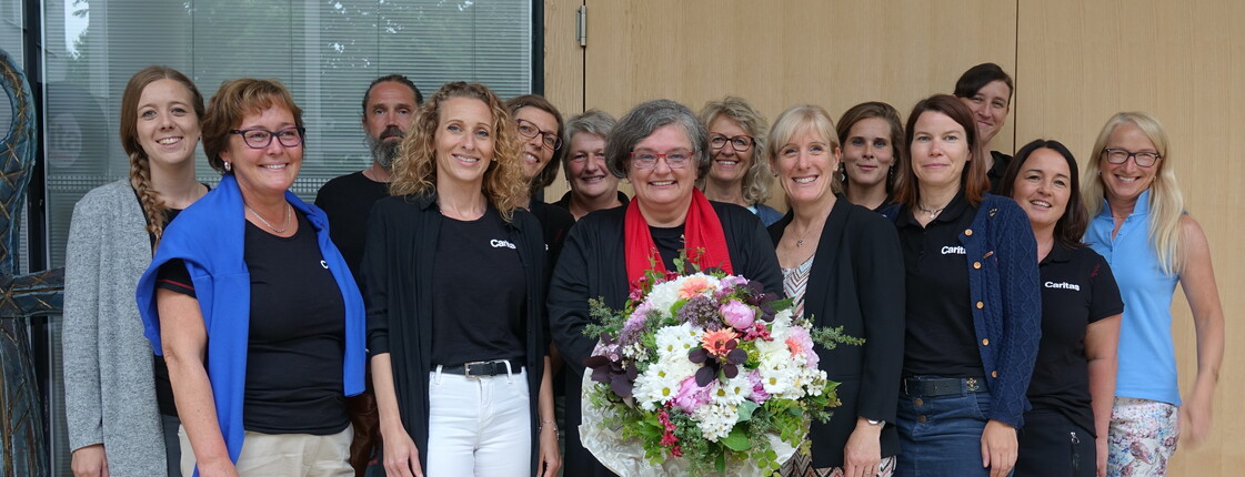 Mitarbeiter*innen der Sozialpädagogischen Familienhilfe der Caritas stehen zu einem Gruppenfoto zusammen.