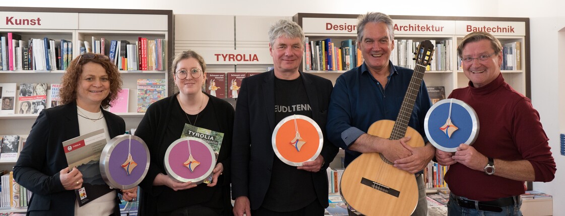 Gruppenfoto von fünf Personen vor einem Bücherregal.