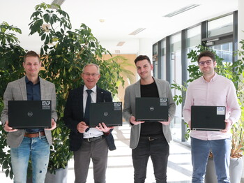 Gruppenfoto von vier Männern mit Laptops in den Händen.