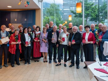 In einem Veranstaltungsraum mit großer Glasfassade stehen viele Personen zu einem Gruppenfoto zusammen.
