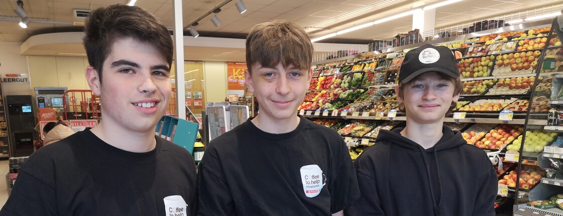 Drei Schüler stehen in einer SPAR-Filiale zu einem Gruppenfoto zusammen.