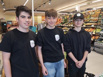 Drei Schüler stehen in einer SPAR-Filiale zu einem Gruppenfoto zusammen.