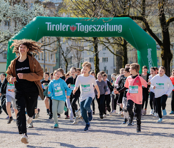Viele Schüler*innen laufen einem youngCaritas Mitarbeiter hinterher.