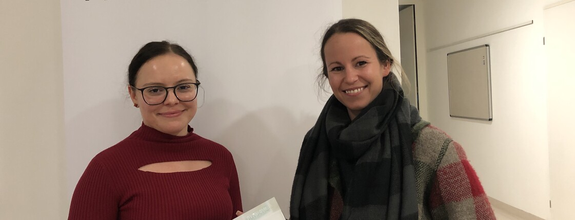 Zwei Frauen stehen vor einenm Roll-Up zu einem Foto zusammen.