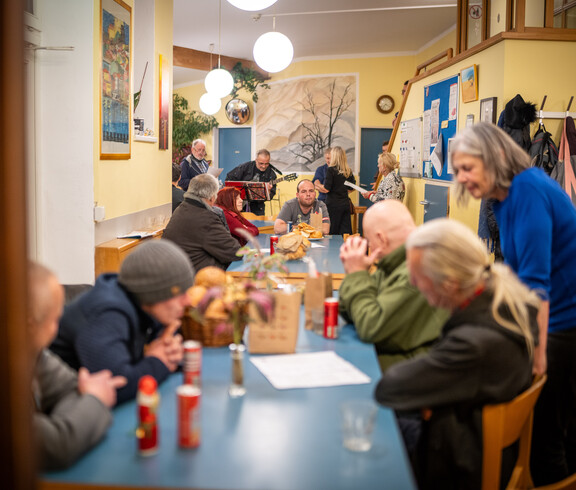 Viele Personen stehen und sitzen in einem großen beisammen und unterhalten sich.