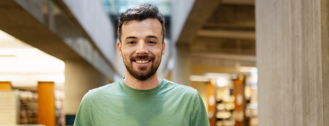 Portrait eines jungen Mannes mit grünem T-Shirt und Tablet in den Händen.