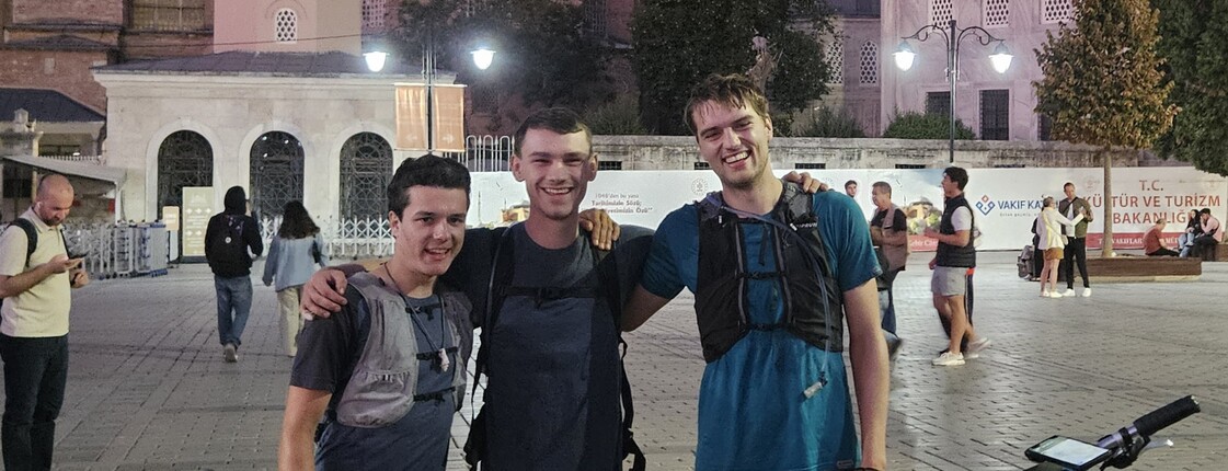 Drei Männer stehen hinter einem Tandemfahrrad vor der Blauen Moschee in Istanbul.