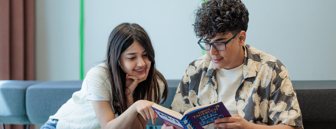 Ein Junge und ein Mädchen sitzen auf einem Sofa und lesen in einem Buch.