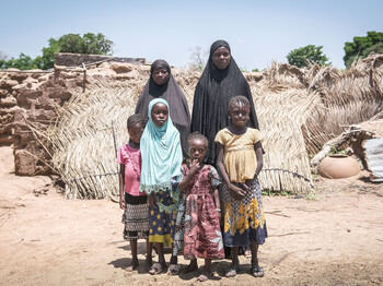 Gruppenfoto von zwei Frauen mit ihren Töchtern vor den Trümmern einer Siedlung in Burkina Faso.