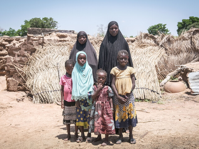 Gruppenfoto von zwei Frauen mit ihren Töchtern vor den Trümmern einer Siedlung in Burkina Faso.