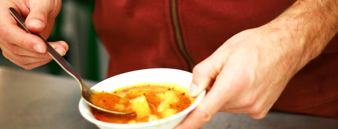 Samstagskochen im JuZe Space Ein Mann, der einen roten Hoodie trägt, löffelt in einer Schüssel mit Kartoffelsuppe.