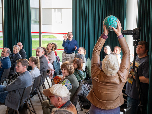 Eine Frau bei einer Veranstaltung fängt einen Ball, der ihr von einer anderen Teilnehmerin zugeworfen wird.