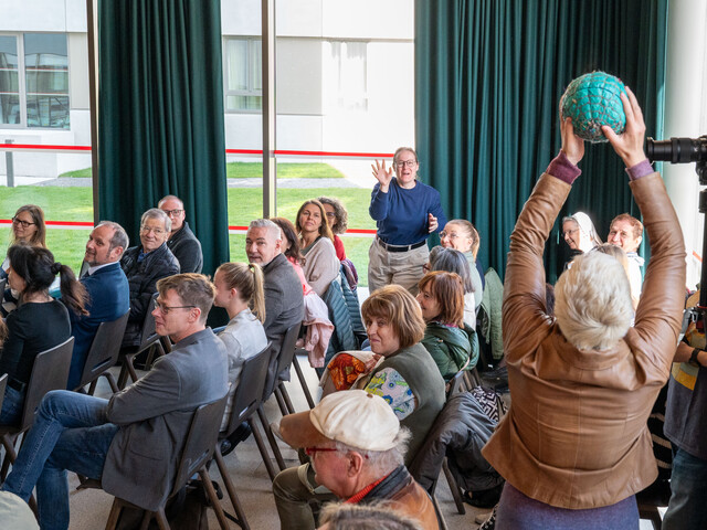 Eine Frau bei einer Veranstaltung fängt einen Ball, der ihr von einer anderen Teilnehmerin zugeworfen wird.