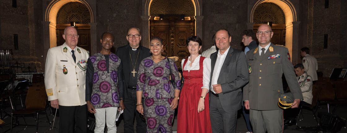 Sieben Personen stehen vor einem großen Gebäude zu einem Gruppenfoto zusammen.