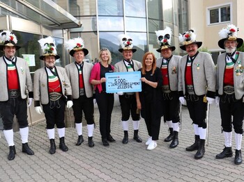 Neun Personen stehen bei einer Spendenübergabe für ein Gruppenfoto zusammen