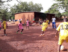 In den Ferien besuchen viele Kinder Feriencamps in denen Fußball stets auf der Tagesordnung steht.  Kinder spielen Fußball in einem Ferienlager auf einem Sandplatz.