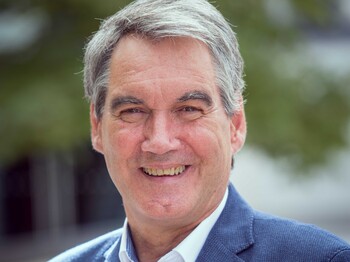 Portrait eines Mannes, der einen blauem Anzug trägt.