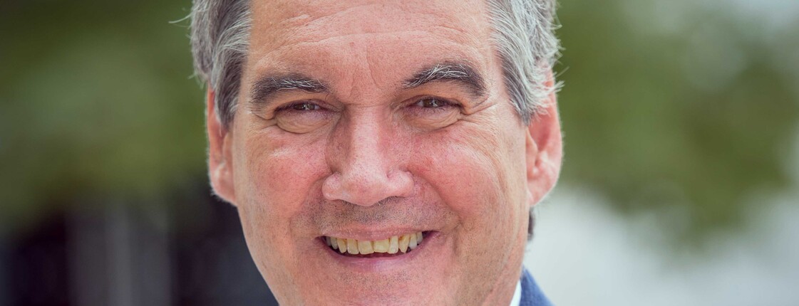 Portrait eines Mannes, der einen blauem Anzug trägt.