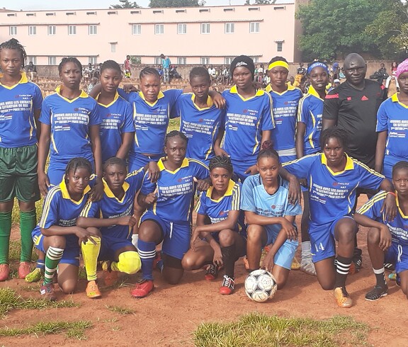 Es ist bemerkenswert, dass fast die Hälfte der Fußballteams bei der Fußballmeisterschaft von Mädchen gebildet wird.  Ein Mädchenfußballteam in blauen Trikots posiert gemeinsam mit Trainern für ein Gruppenfoto.