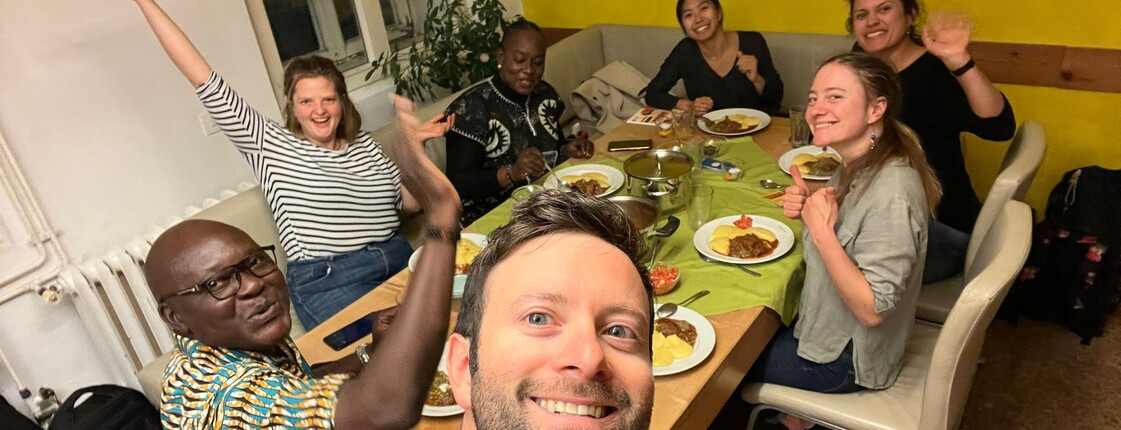 Selfie von sieben Personen, die an einem Tisch sitzen und zu Abend essen.