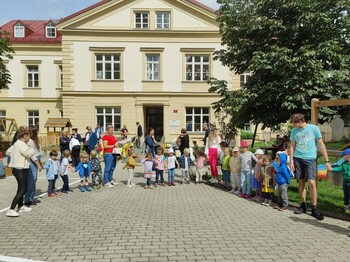 Viele Kinder stehen vor einer Kinderbetreuungseinrichtung in der Reihe und halten Hände.