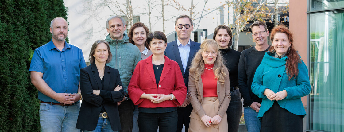 Zehn Personen stehen in einem Innenhof zu einem Gruppenfoto zusammen.