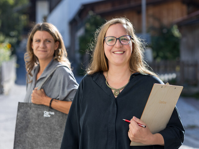 Portrait zweier Haussammlerinnen mittleren Alters, die in einer Dorfstraße stehen.