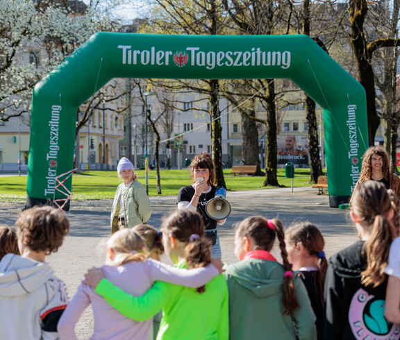 Eine Frau mit Megafon steht vor einer Gruppe Schulkinder.