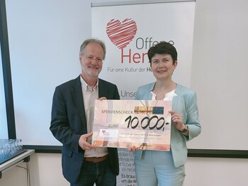 Zwei Personen halten gemeinsam einen Spendenscheck über 10.000 Euro in den Händen.