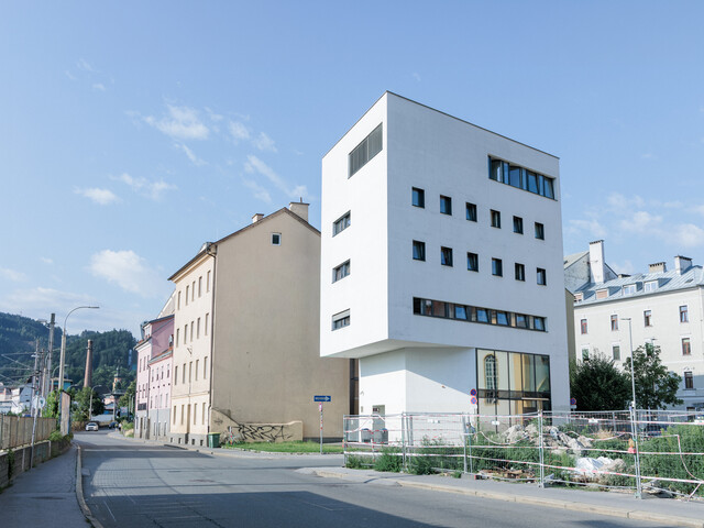 Ein weißer Neubau steht in einem Bahnhofsviertel zwischen alten Gebäuden.