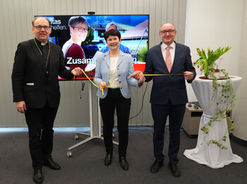 Drei Personen stehen zu einem Gruppenbild zusammen