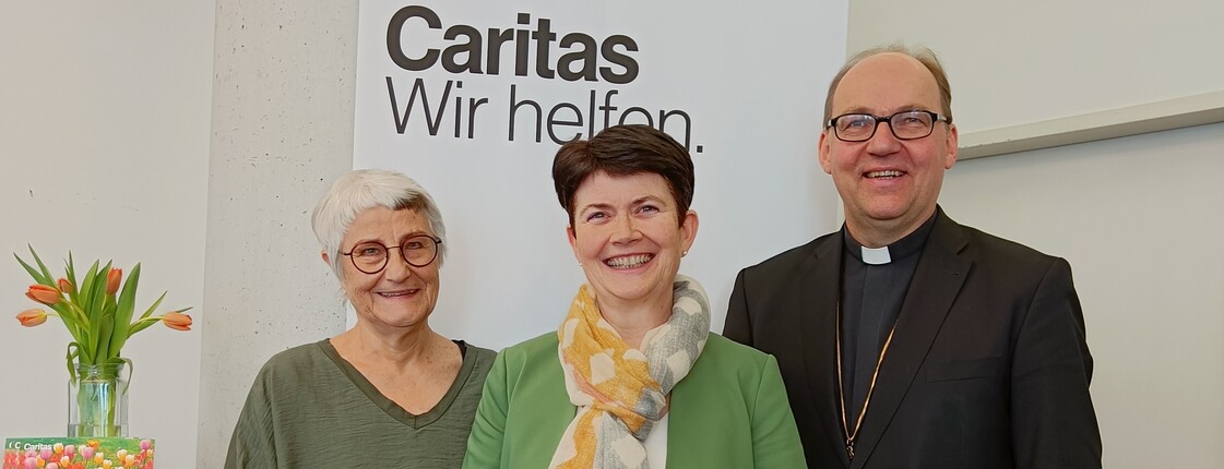 Portrait dreier Personen vor einem Roll-Up.