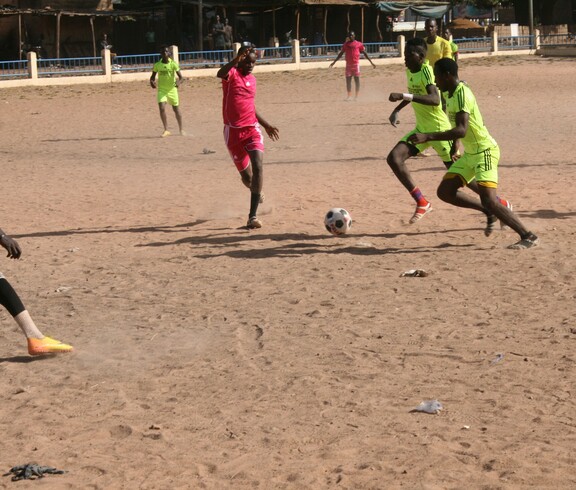 Fußball unterstützt Straßenkinder, traumatische Erfahrungen zu verarbeiten und Teamgeist zu entwickeln. © Caritas Zwei Spieler kämpfen während eines Fußballspiels auf Sandboden um den Ball.