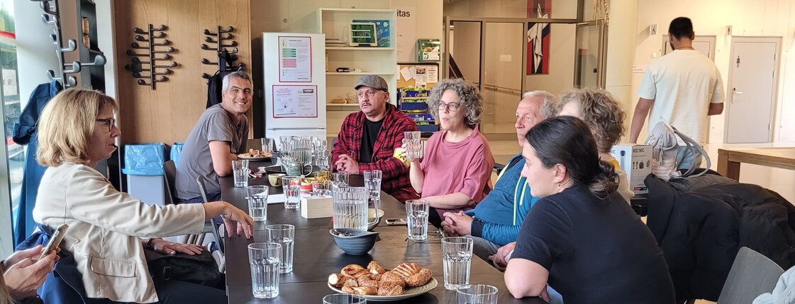 Fünf Personen sitzen in einem Neubau an einem Tisch und schauen in die Kamera.