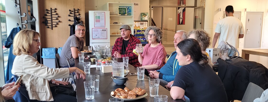 Fünf Personen sitzen in einem Neubau an einem Tisch und schauen in die Kamera.